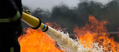 Firefighter spraying a fire with foam hose