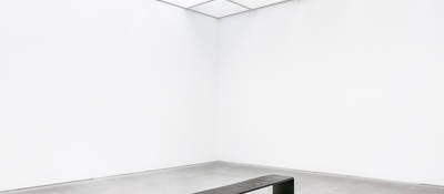 A black bench set in the middle of a white room.