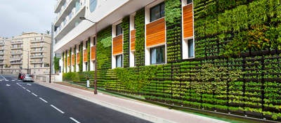 Sustainable urban building with exterior garden walls, large windows, and wood paneling