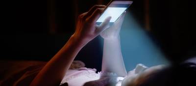 Blue light filters onto a mobile phone user as she surfs for information.