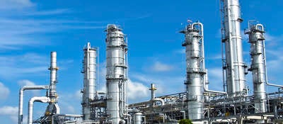 Energy processing facility against a blue sky with drifting clouds