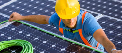 man in hard hat doing wiring on a solar energy panel for wire and cable testing and certification