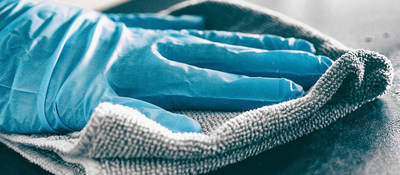 Photo of a person wearing gloves sanitizing a surface
