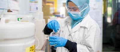 Female scientist in hijab and face mask works in a laboratory.