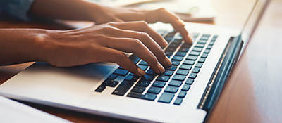 Photo of a person typing on a laptop