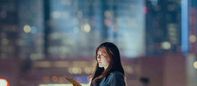 Woman outside on rooftop alone with cityscape in the background.