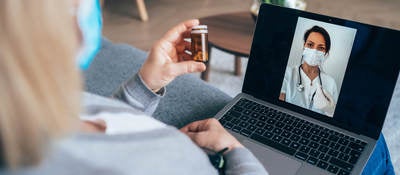 Senior woman isolated at home due to coronavirus epidemic having video call with family doctor, consulting about medicine