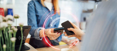 Woman tapping smartphone with another smartphone for payment