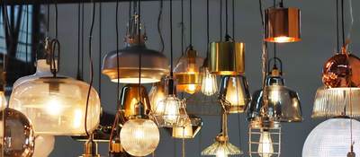 Variety of lamps and lightbulbs hanging from ceiling 