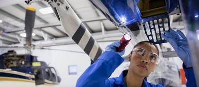 Female helicopter mechanic examining part with flashlight