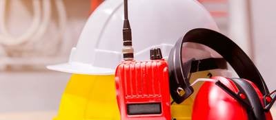 Construction hat, walkie talkie and earphones sitting on building plans
