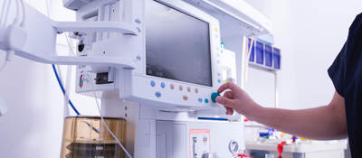 Technician monitoring equipment in hospital operating room