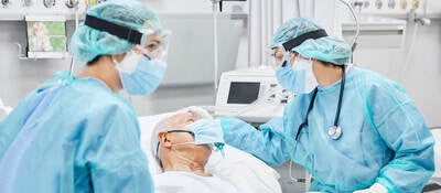 Medical professionals wearing personal protection equipment (PPE) attending to a hospital patient