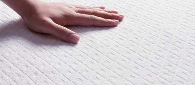 Human hand touching a mattress top