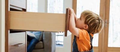A child pulling on an open dresser drawer, a furniture tip-over risk