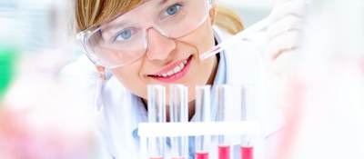 Female scientist dripping liquid into vials 