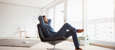 Man relaxing in an armchair conveying a sense of peace of mind, comfort and wellness.