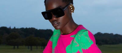 Woman wearing pink and green dress and sunglasses