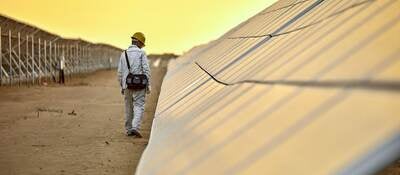 Outdoor solar pnael test facility with golden sky  and with man inspecting PV solar panels
