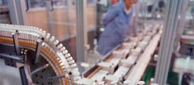 A syringe factory with a worker in the background