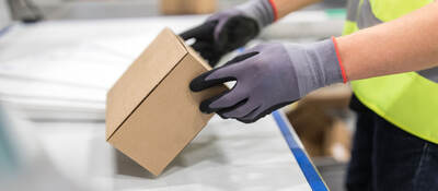 Worker checking package from conveyor belt in warehouse