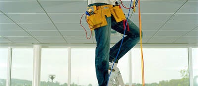 Man on step ladder, working through gap in ceiling, low section