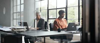 Two people working sided by side on laptops