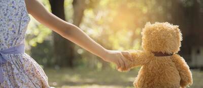 Young girl holding hands with a teddy bear