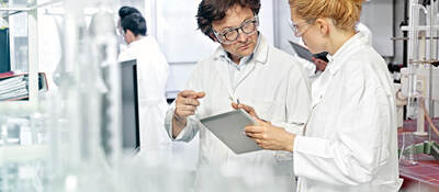 Two scientists working on a tablet in a lab