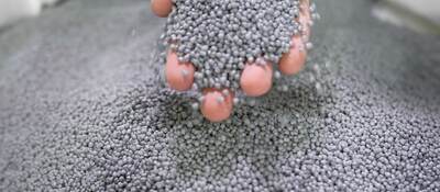 A person's hand holding plastic pellets
