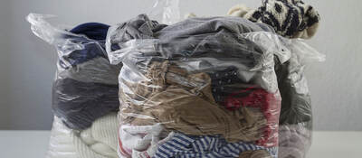 Clothes in plastic bags conveying promotion of recycling clothing, give it second life than become waste
