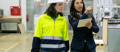Female plant manager with tablet and middle-aged woman in hardhat
