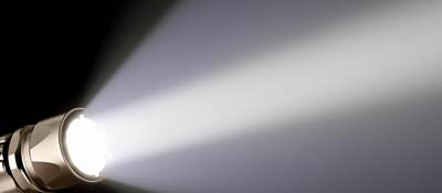 A piercing beam of light from a handheld flashlight.