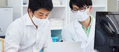 Life science researchers examining data on a laptop computer. 