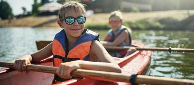 Children in life jackets rowing a canoe.