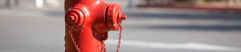 A bright red fire hydrant along a road.