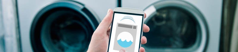 A man using his phone thats connected to a washing machine