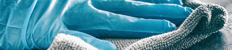 Photo of a person wearing gloves sanitizing a surface