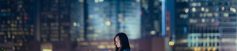 Woman looking at her tablet at night in the city