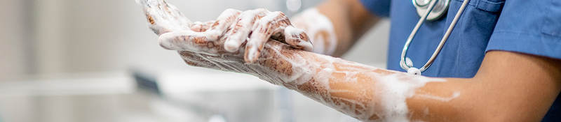  Female medical professional scrubbing hands with disinfectant soap