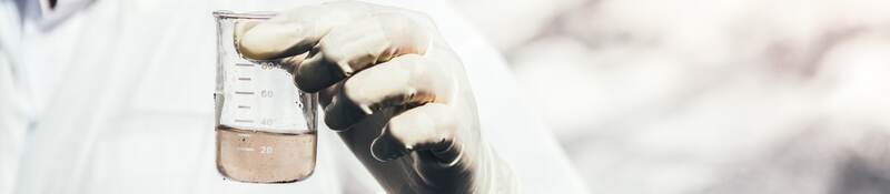 Person in protective suit examining polluted water