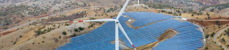 solar panels on rolling hills with two wind turbines