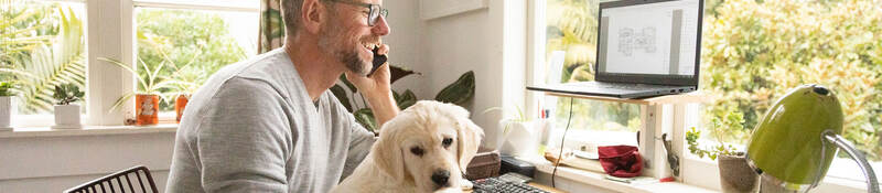 Person smiling and working from home with cute yellow puppy on their knee