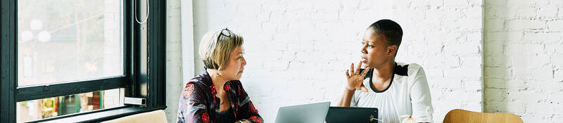 Two people sitting at a table discussing a topic