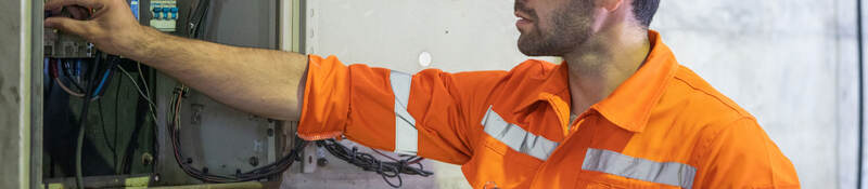 An electrician working at a circuit electrical panel.
