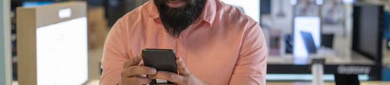 Young man testing out a mobile phone.