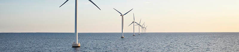 Wind farm at sea at sunset
