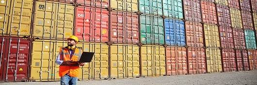 |man standing in front of multiple cargo containers