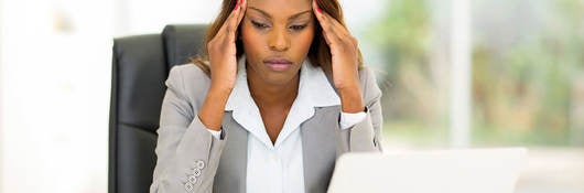 Stressed businesswoman sitting in office rubbing her head