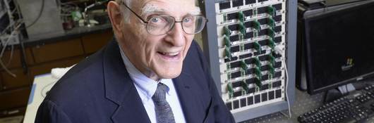 John Goodenough sitting in his lab in front of lab equipment